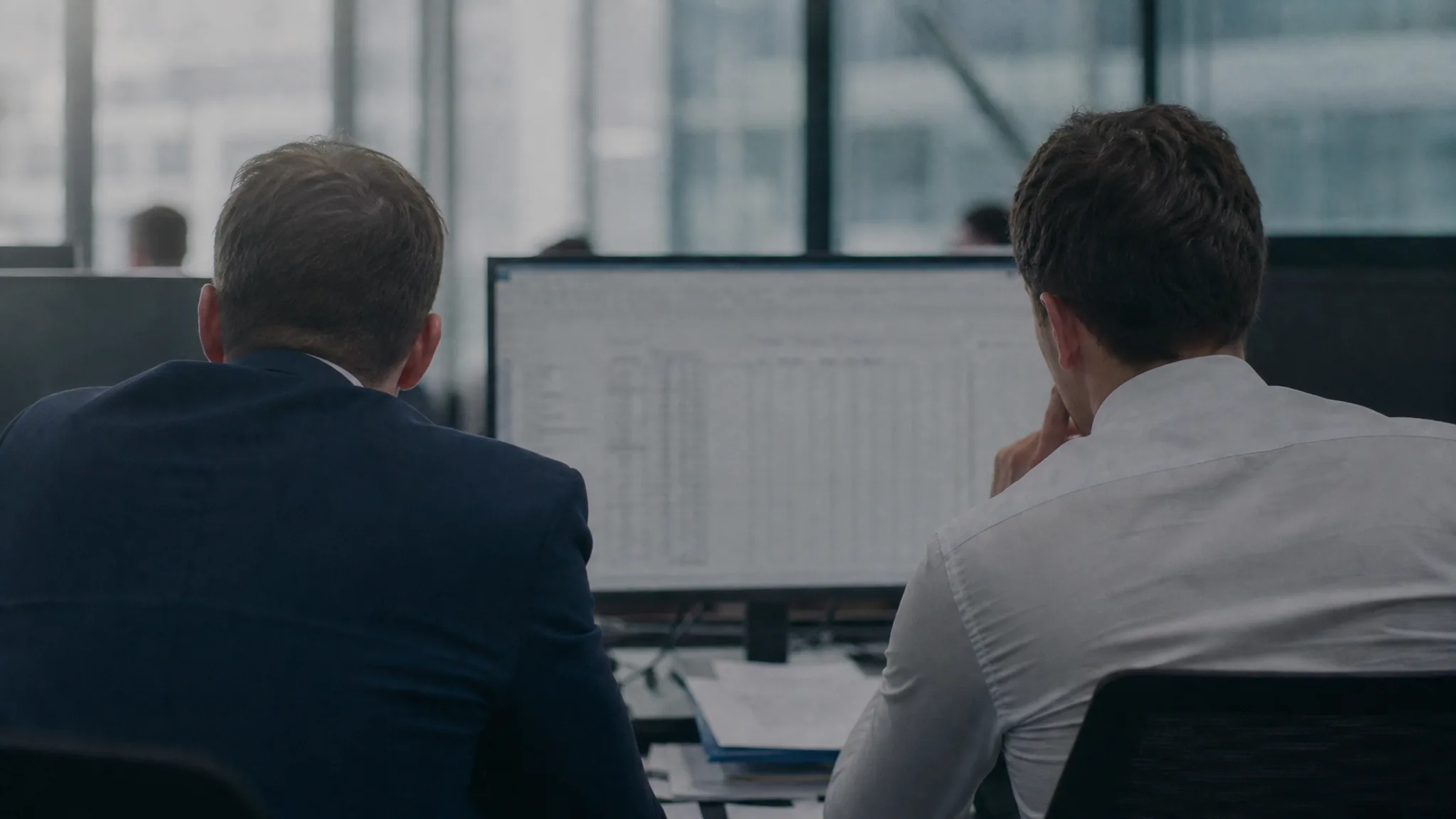 Two finance colleagues reviewing receivables on a monitor